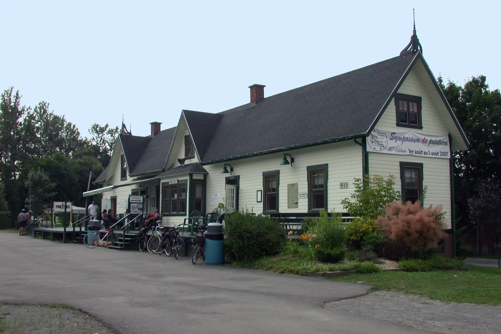 L’ancienne gare de bois de Prévost, ses pignons et son quai, des vélos garés devant.
