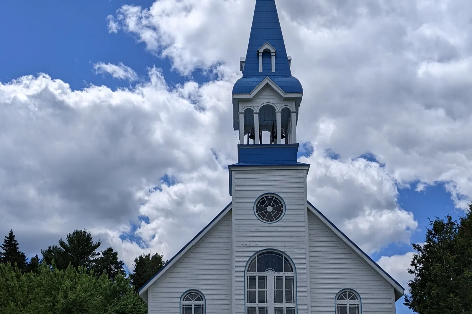 La façade blanche de l’église de Saint-Adolphe-d’Howard et son clocher bleu.