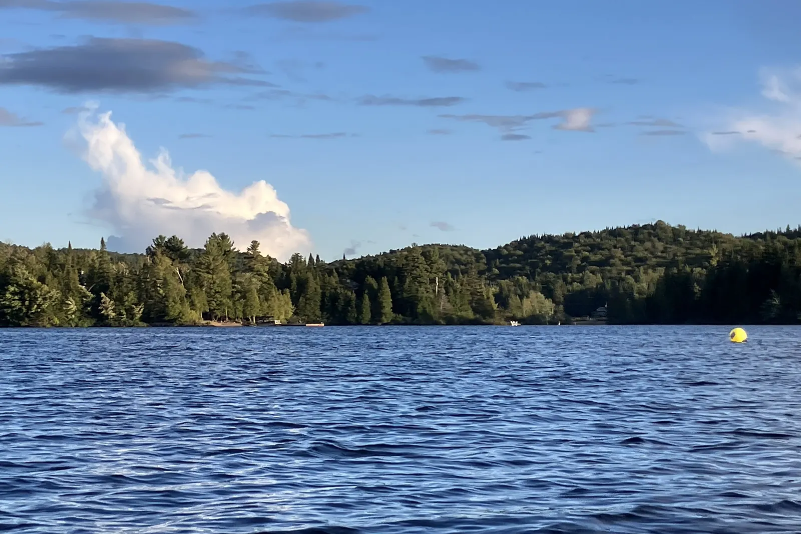 Le lac Saint-Joseph, sa rive boisée et un grand ciel d’été.
