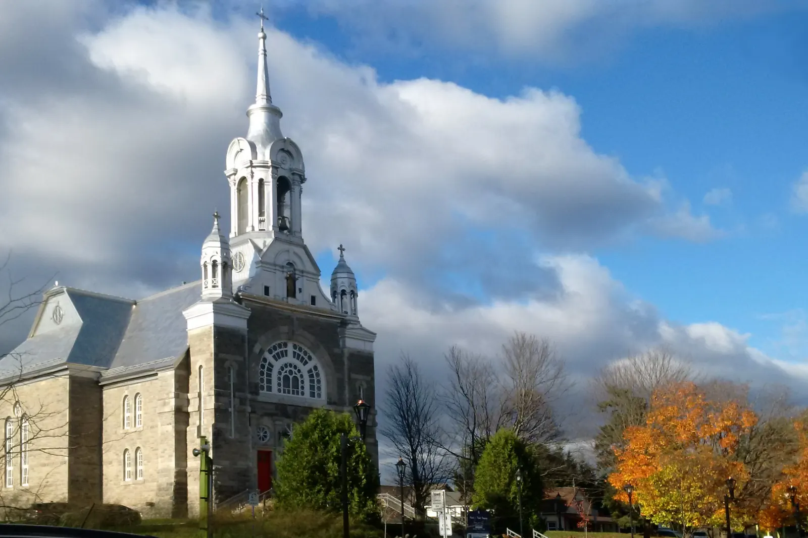 L’église de pierre de Saint-Sauveur et son clocher, entourée d’arbres d’automne.
