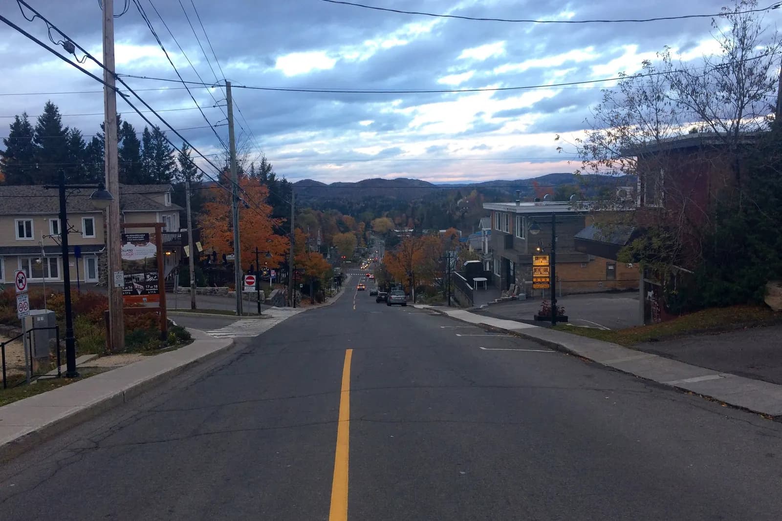 La rue Morin à la tombée du jour, ses commerces et les collines au bout de la rue.