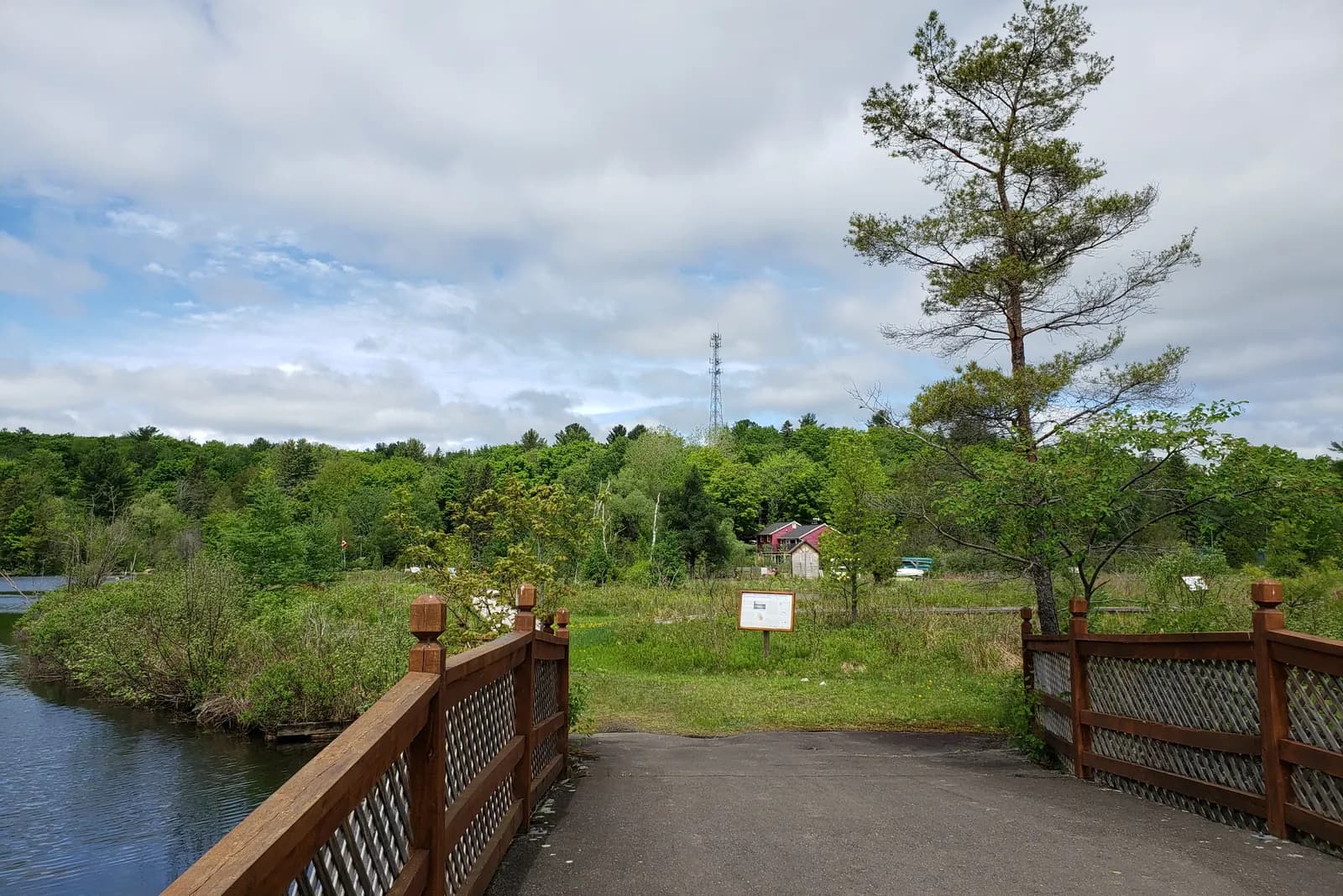 Un pont de bois mène à l’île Benoit par-dessus un canal, la forêt autour.