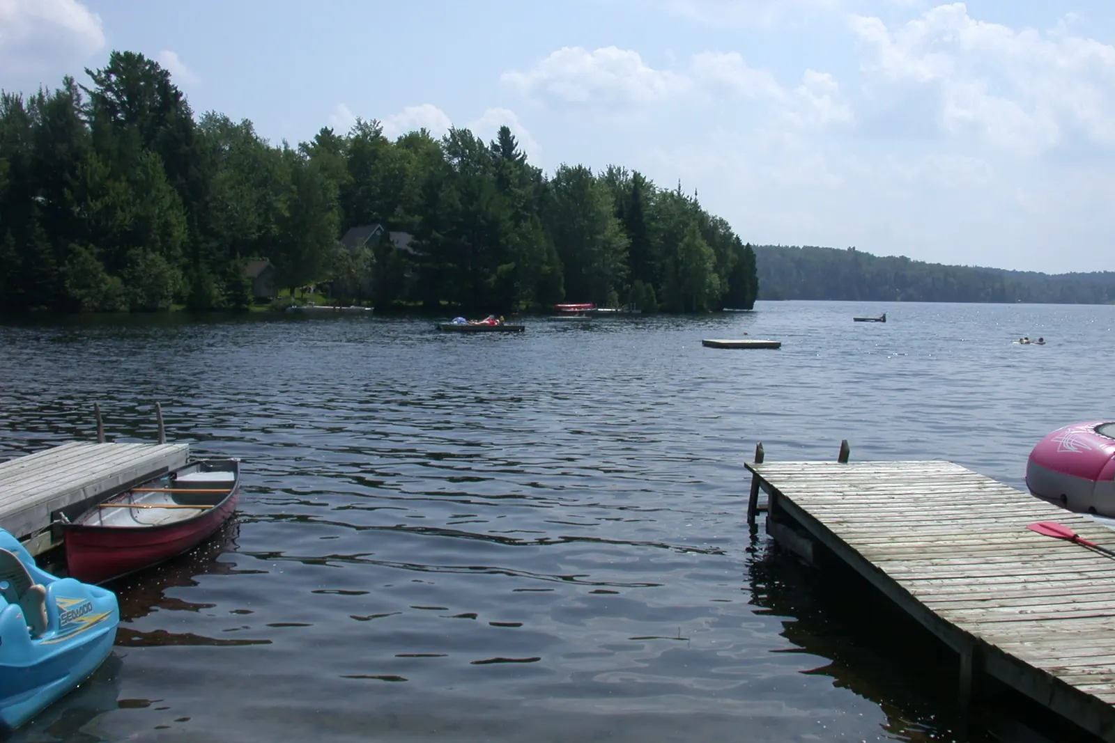 Des quais, un canot et un pédalo au bord du lac Marois, la rive boisée au loin.